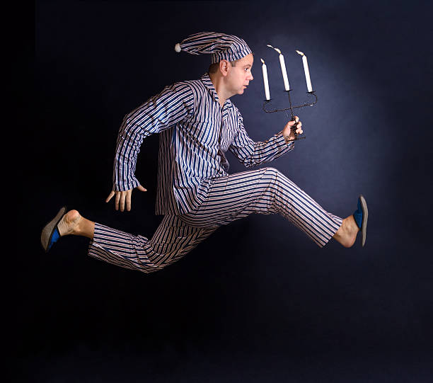 man in pajamas running with a candlestick stock photo
