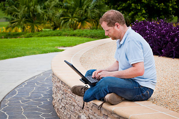 Man in park using laptop computer stock photo