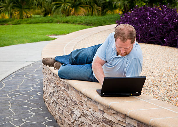 Man in park using laptop computer stock photo