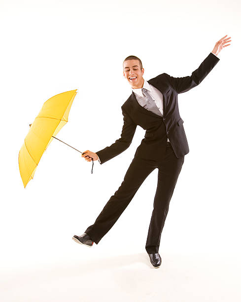 Man in suit with yellow umbrella doing funny business stock photo