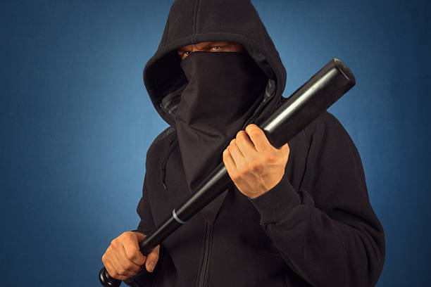 Man in the mask holds bat Dangerous man in the mask with baseball bat ready for fight sports bat stock pictures, royalty-free photos & images