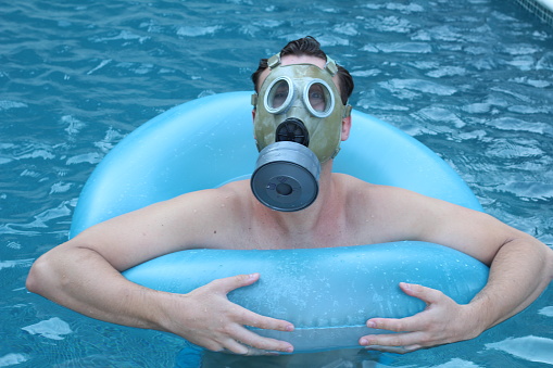 Man in the pool with gas mask.