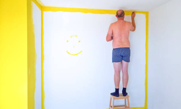 Man in underwear painting the walls of a room stock photo