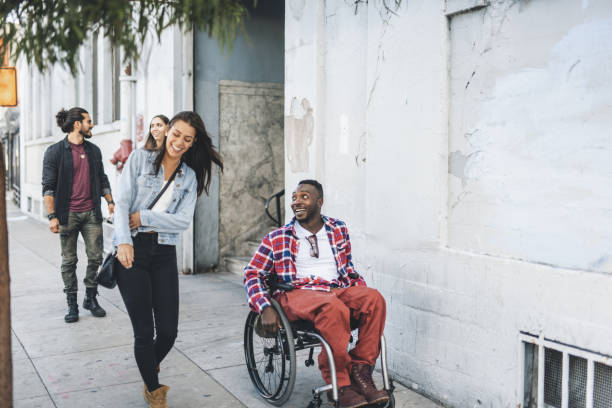 man in wheelchair with his three friends outdoors - wheelchair street happy imagens e fotografias de stock