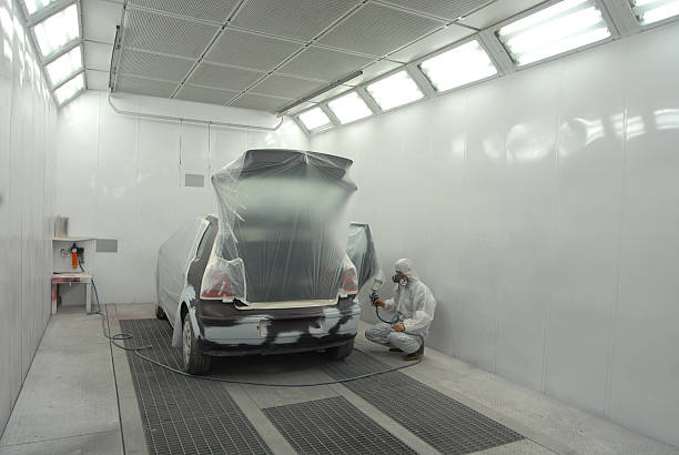 Man in white garage painting automobile stock photo