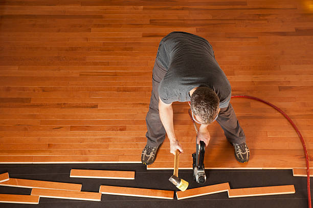 Man installing a wood floor shown from above Top view of a man installing planks of hardwood floor hardwood stock pictures, royalty-free photos & images