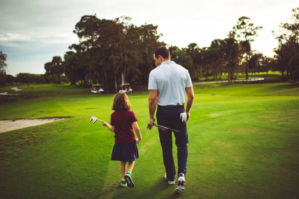 Man instructs girl on golf course, father or coach stock photo