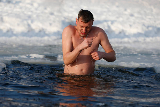 en man är störtade in i ett ishål. bada i isvatten. jesu dop. religiös helgdag - ice bath ocean bildbanksfoton och bilder