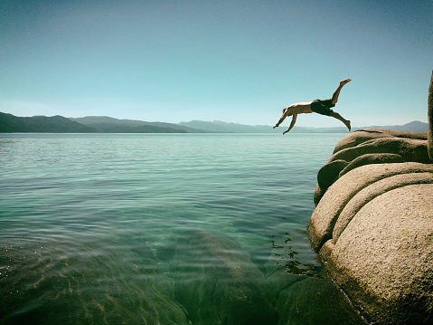 Man diving off rocks into Lake Tahoe