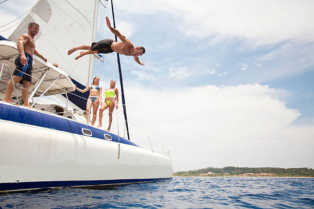 Man jumping off sailboat into Caribbean Sea  catamaran stock pictures, royalty-free photos & images