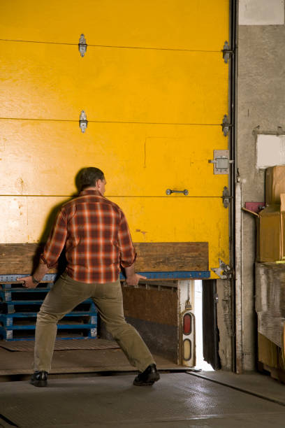 man lifting door at warehouse - garagem abrindo imagens e fotografias de stock