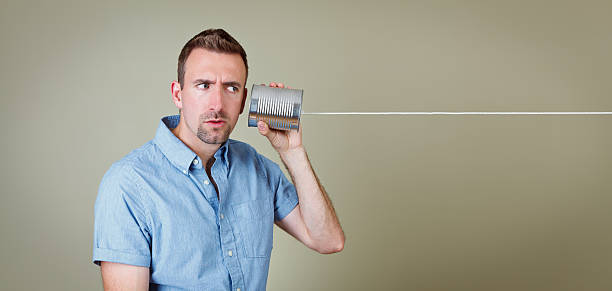 Man listening to tin can telephone stock photo