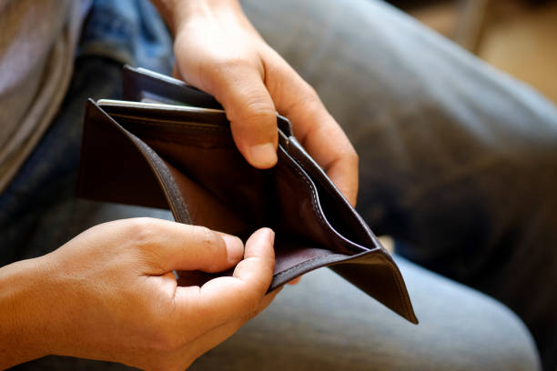 Man looking at his empty leather wallet in office. stock photo