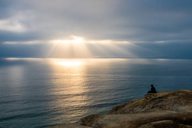 Man Looking Out at Ocean at Rays of Light stock photo