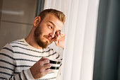 Man looking through the window holding cup of coffee