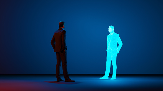 Man stands in a room looking at a clone or avatar of himself. The clone is shown as a hologram. Concept image of future living where cloning becomes normal.
