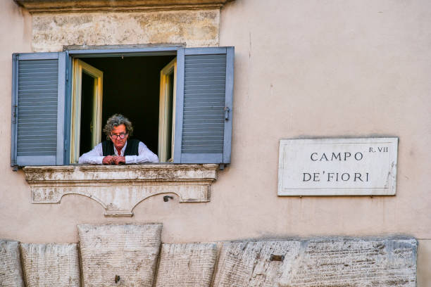 A man looks out of a window in Campo de Fiori square in the heart of Rome stock photo