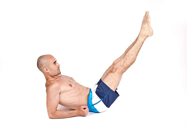 Man lying down doing lower abs exercise lifting legs up. stock photo