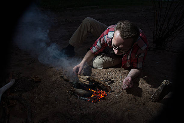 man making firecamp outdoors at night. - reigate stockfoto's en -beelden