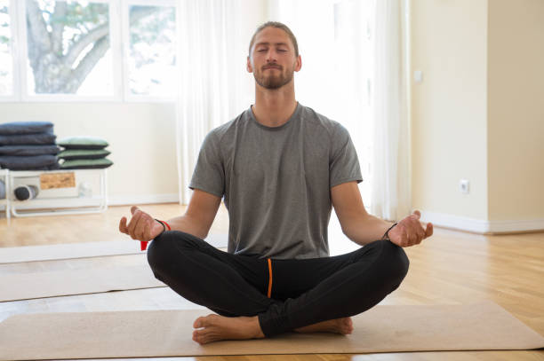 Man meditating and holding hands in mudra gesture in class stock photo
