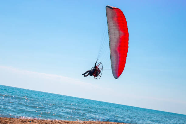 A man on a motor paraglider in the blue sky over the sea, the slope of the horizon. Sports and passion for flying stock photo