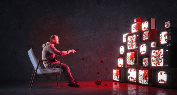 man on an armchair watching many televisions stock photo