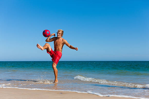 homem a jogar futebol na praia - futebol de praia imagens e fotografias de stock