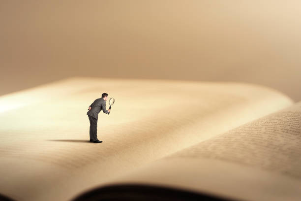 Man On Giant Book With Magnifying Glass stock photo