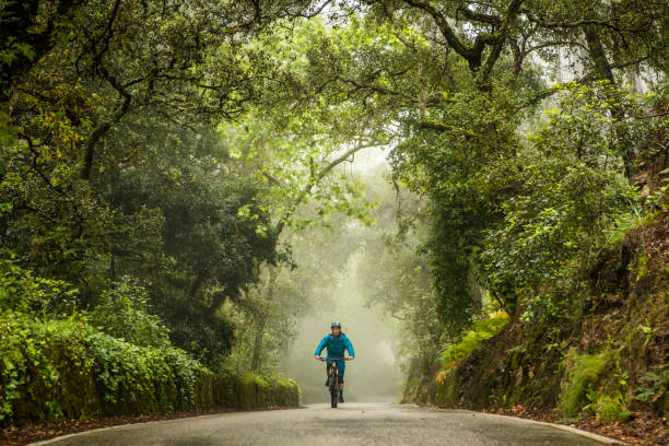 Man on mountain bike riding in the middle of rural road. stock photo