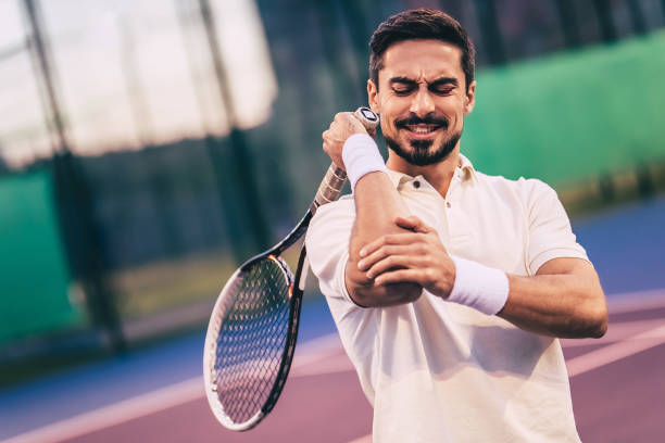 Man on tennis court. Handsome man on tennis court. Young tennis player. Pain in the elbow elbow stock pictures, royalty-free photos & images