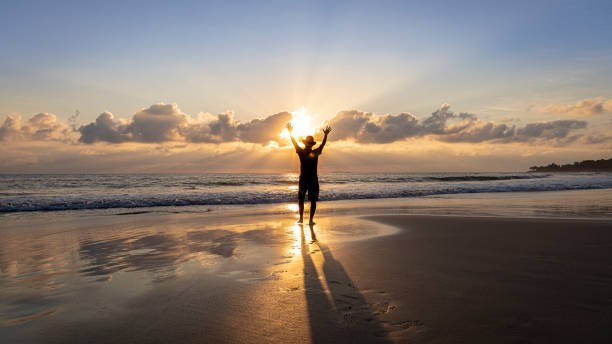 Man on the beach celebrating victory against sickness stock photo
