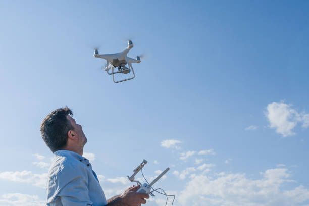 man werking van vliegende drone quadrocopter - man,standing, elevated view,remote control stockfoto's en -beelden