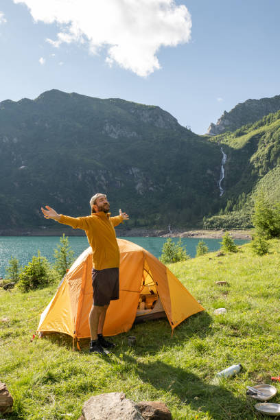 Man outside tent stretching arms out stock photo