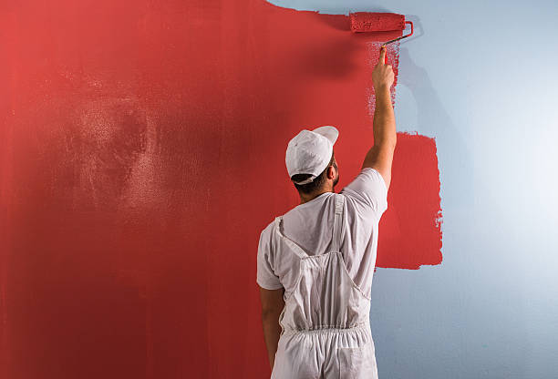 Man painting wall with roller stock photo