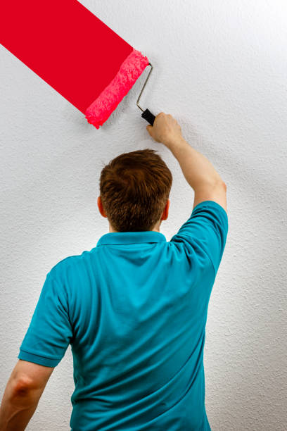 Man paints wall red, close up stock photo