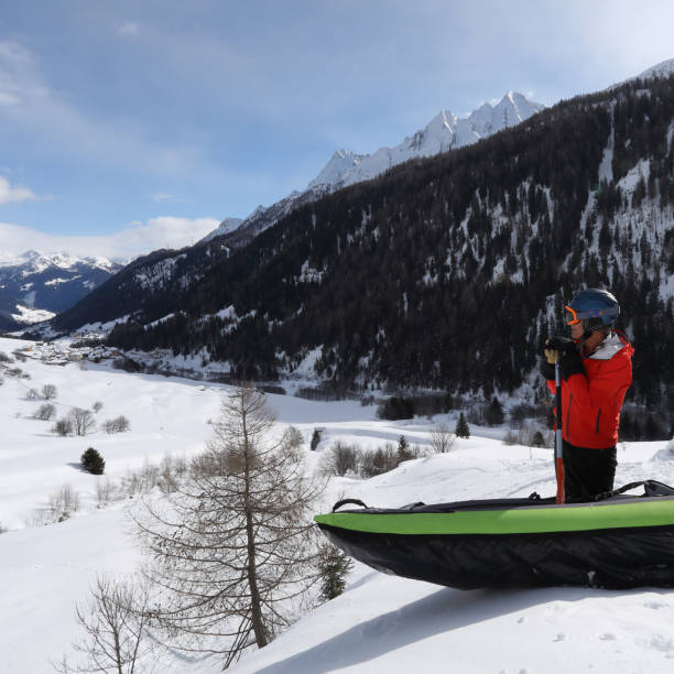 Photo of Man pauses beside inflatable kayak on snow summit