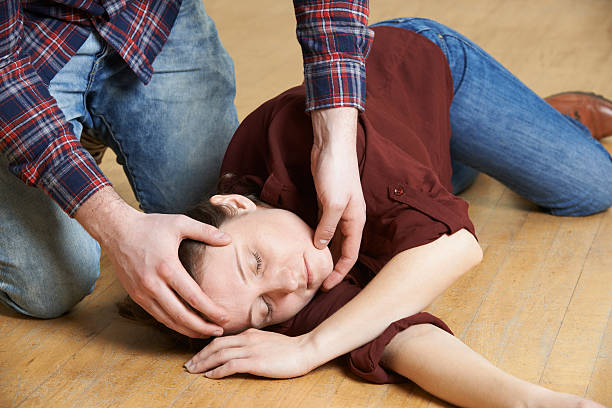 Man Placing Woman In Recovery Position After Accident stock photo