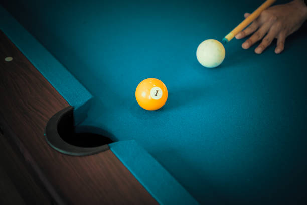 Man playing billiards try to put yellow ball to hole stock photo