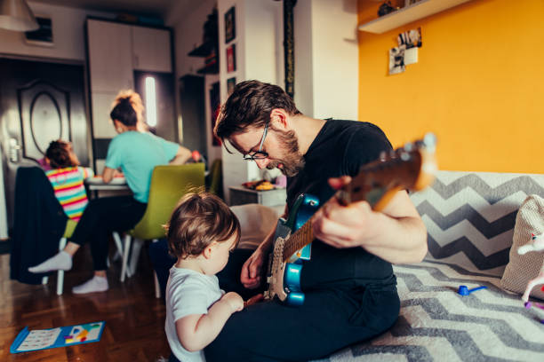Man playing guitar to his son stock photo
