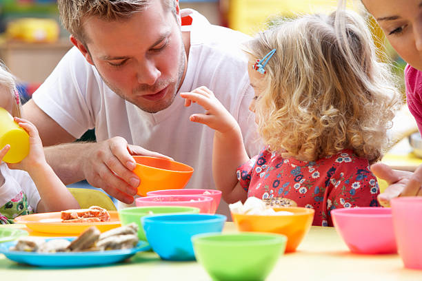 Man playing with children using colorful cups stock photo