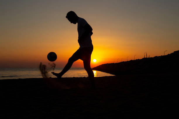 男はビーチでボールで遊びます。 ストックフォト