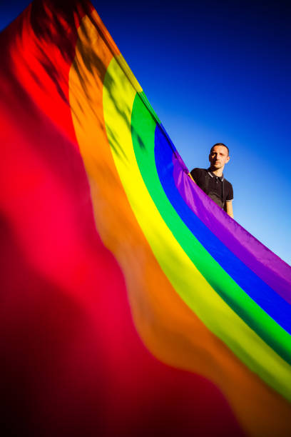 Man posing with large rainbow flag. LGBTQ concept stock photo