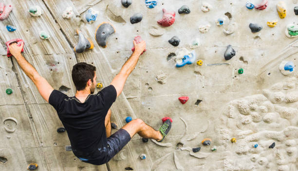 Man practicing rock climbing on artificial wall indoors. Active lifestyle and bouldering concept. A Man practicing rock climbing on artificial wall indoors. Active lifestyle and bouldering concept. crag stock pictures, royalty-free photos & images