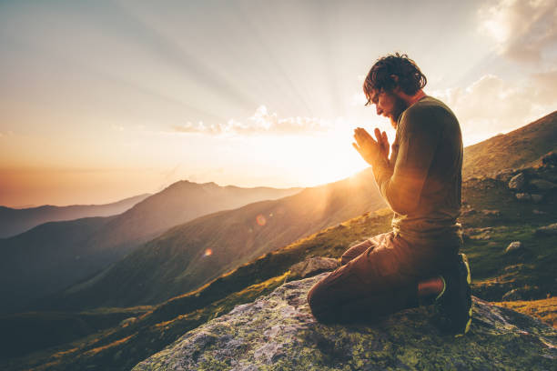 Man praying at sunset mountains Travel Lifestyle spiritual relaxation emotional concept vacations outdoor harmony with nature landscape stock photo