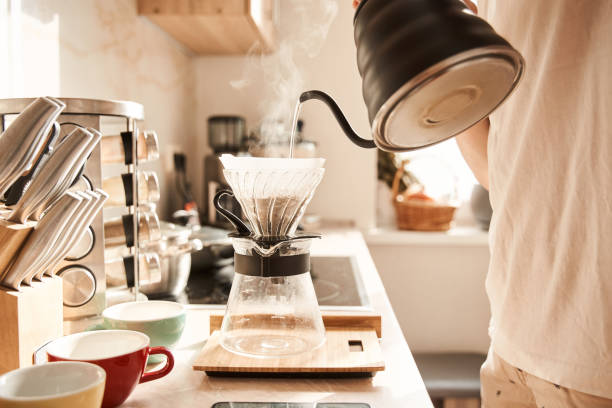 Man preparing coffee for himself and his boyfriend while standing at kitchen stock photo