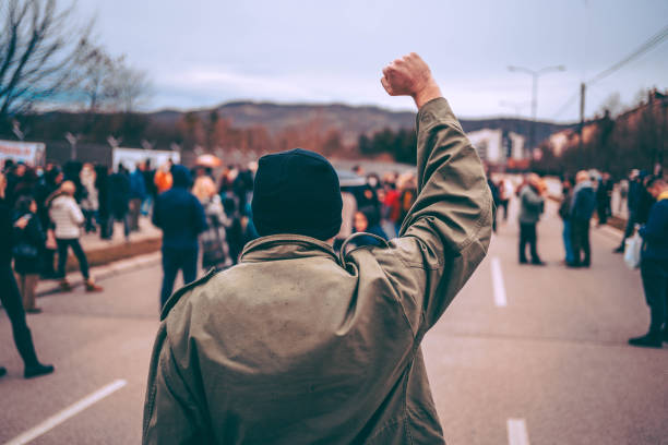 el hombre protesta en la calle con el puño levantado - protest fotografías e imágenes de stock