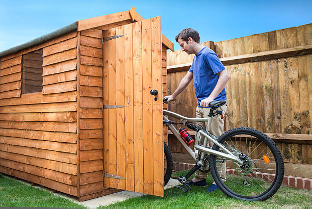 Man pushing his bike into a shed. stock photo