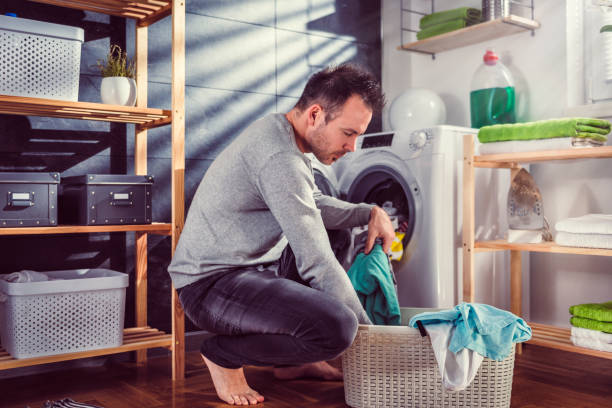 Man putting clothes into washing machine stock photo
