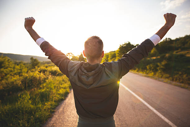 Man raising arms Sport and life achievements and success concept. Sporty man raising arms towards beautiful sunset on the road one man only stock pictures, royalty-free photos & images