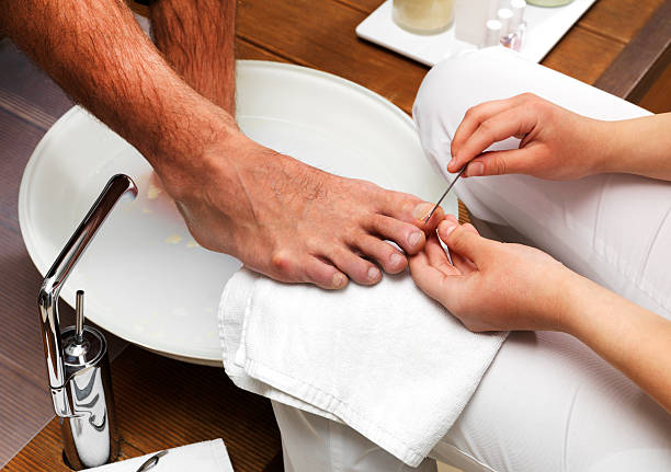 Man receiving a foot care treatment Men's Foot Care In The Beauty Parlour (Pedicure) man pedicure stock pictures, royalty-free photos & images